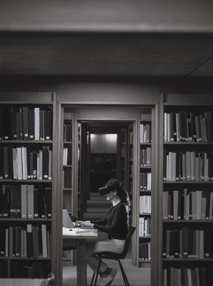 photo of a woman in a library with a laptop and a VR headset